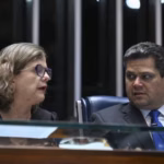 Senadora Teresa Leitão e senador Davi Alcolumbre conversam, sentados lado a lado no plenário do Senado Federal, em Brasília, durante sessão legislativa. Teresa usa óculos e Alcolumbre veste terno escuro e gravata azul.